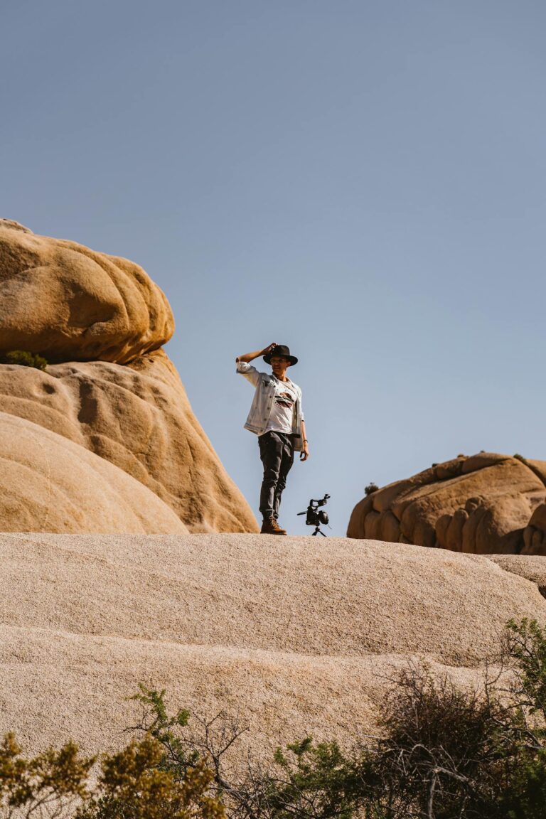 A man stands atop desert rock formations, capturing the essence of adventure in a natural landscape.